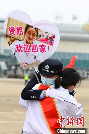 3月23日下午,一名医疗队队员与举着贴有自己照片牌子的民警妹妹相拥。 刘占昆 摄 369名队员凯旋!江西对口支援随州医疗防疫队返赣